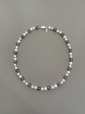 pryte Multicolor Abyss Necklace with cream, pink, and black beads on a gray background